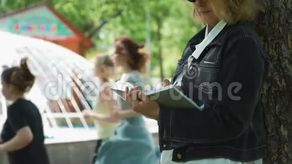 女人在公园的笔记本上记笔记视频的预览图