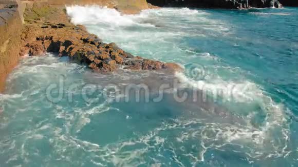 蓝色的海浪拍打着海岸的黄色石头大量白色泡沫和喷雾形式概念视频的预览图