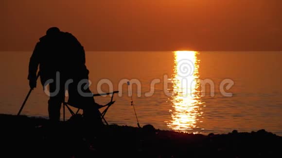 日落时分海边渔夫的剪影钓鱼椅钓鱼竿日落小径视频的预览图