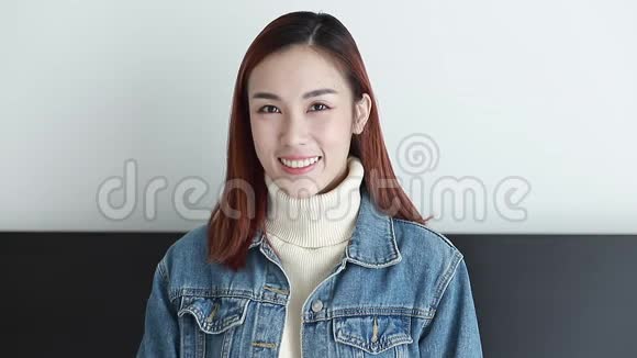 美丽的亚洲黑发女子穿着牛仔夹克在室内欢笑的肖像视频的预览图