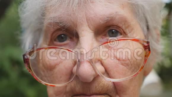 戴眼镜的老妇人看着室外摄像机带有情感和感情的悲伤祖母的肖像奶奶穿着视频的预览图