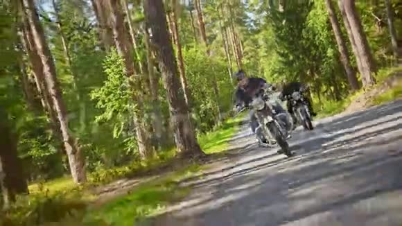 两个戴着头盔骑着摩托车的野蛮人骑着摩托车在森林里一个摄像机跟踪着骑自行车的人视频的预览图
