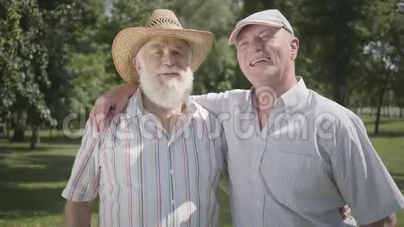 两个积极的老人在公园里挥舞着手看着镜头户外休闲成熟的人在休息视频的预览图
