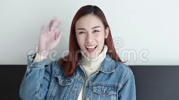 美丽的女人穿着牛仔裤夹克微笑着挥手告别视频的预览图