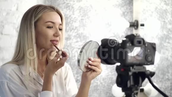 一位漂亮的化妆师正对着镜子在她的嘴唇上涂上唇线视频的预览图