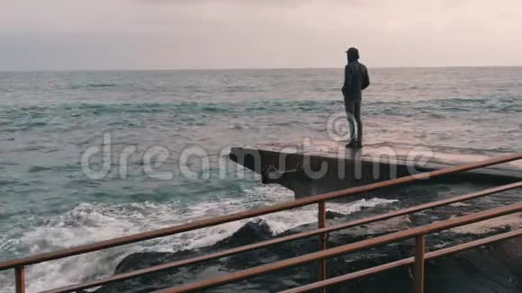 忧郁的小男孩站在码头孤独的男孩看着风雨飘摇的大海海上悲观的人码头黑暗中的小男孩视频的预览图
