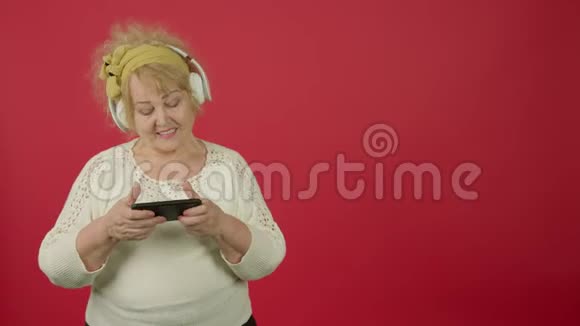 老年超重妇女听耳机音乐和玩智能手机视频的预览图