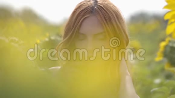 美丽自信性感女孩的肖像红色的头发和绿色的眼睛站在向日葵的田野上美的概念视频的预览图
