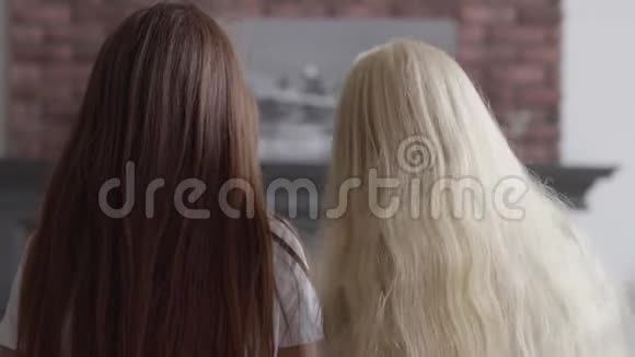 两个留着美丽长发的女孩坐在客厅里的近旁友谊的概念视频的预览图