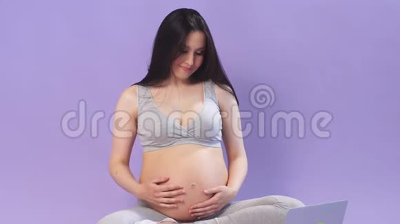 怀孕女商人正在做瑜伽看笔记本电脑上的视频视频的预览图