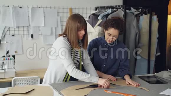 有经验的女裁缝正在教她的助手在织物上勾勒服装图案年轻女性关注视频的预览图
