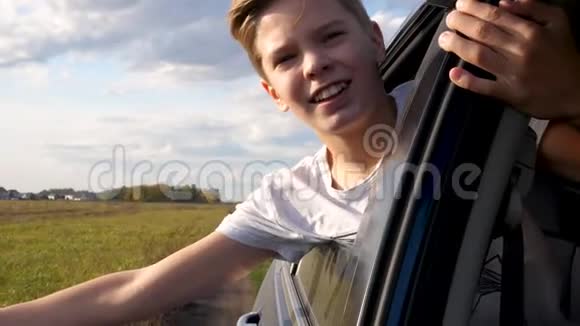 少年男孩望着车窗外挥手汽车正在乡间小路上行驶视频的预览图