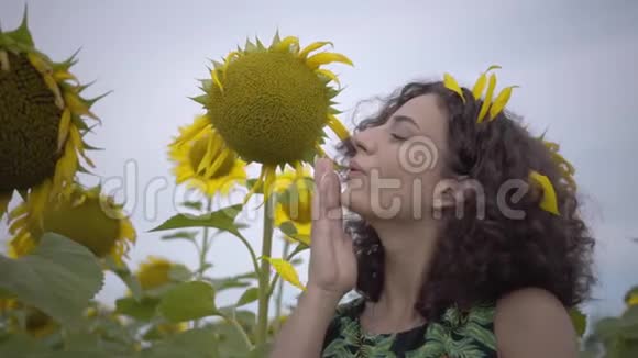 可爱的有趣的卷曲的嬉戏的性感的女人站在向日葵田野上的肖像明亮的黄色自由概念视频的预览图