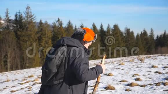 年轻徒步旅行者带着背包和手杖在田野的雪山上攀爬的侧面景色在雪地上徒步旅行的运动员视频的预览图