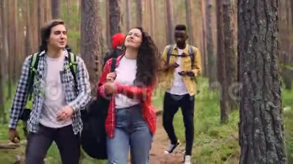 微笑的年轻人朋友们背着背包走在森林里迷人的女孩背着吉他男人和女人都是视频的预览图
