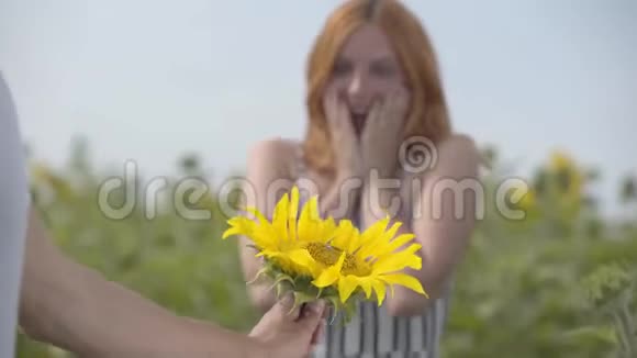 一个面目全非的男人把花送给站在向日葵田野上的姜姑娘浪漫关系视频的预览图