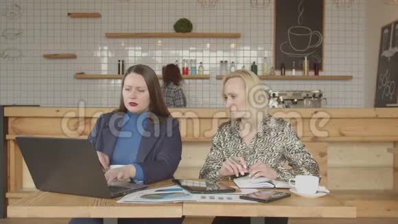两个女商人在咖啡馆里用小玩意联网视频的预览图
