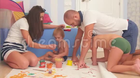 快乐的母亲父亲和他们的小儿子在托儿所里用水彩作画视频的预览图