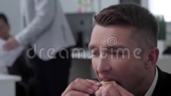 男人在办公室吃饭午餐人们在他身后工作视频的预览图