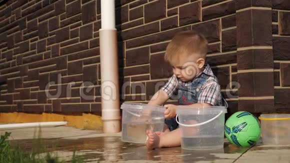 一个短发男孩从塑料桶里倒水视频的预览图