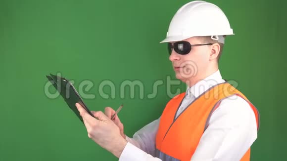 一名男性检查员带着平板电脑在建筑物体上写下并标记注释绿色背景色度键视频的预览图