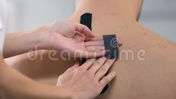 理疗师在男性上背部贴Y形磁带肌肉疼痛视频的预览图