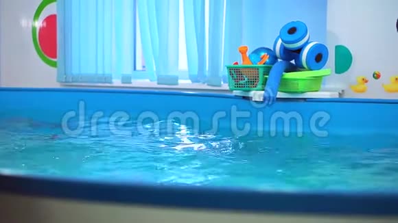 游泳池里那个戴泳镜的男孩跳水了他从底部得到玩具教练训练他潜水视频的预览图