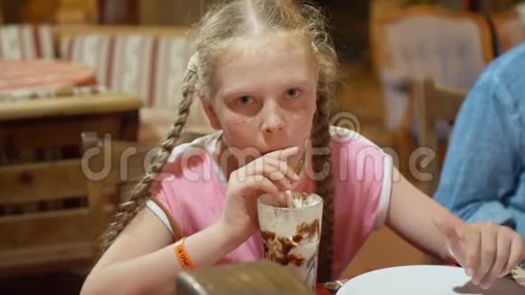 雀斑红发女孩在餐厅桌上喝奶昔少女正在喝牛奶巧克力鸡尾酒视频的预览图