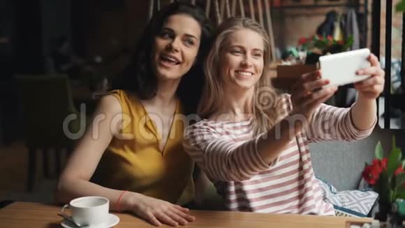 女朋友用智能手机自拍在咖啡馆里做滑稽的表情视频的预览图