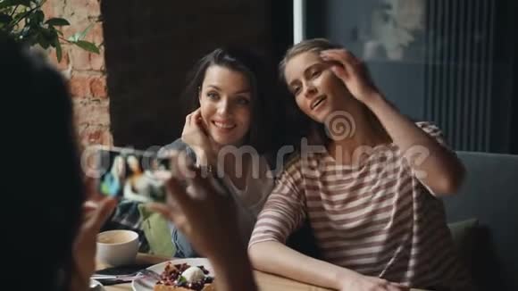 迷人的年轻女性在餐厅拍照摆姿势看智能手机摄像头视频的预览图