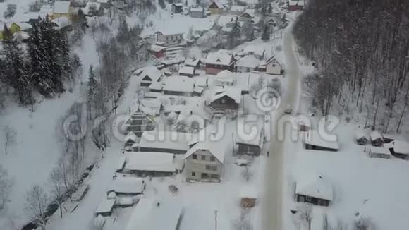 在山村里沿着一条河上的空中冬天的路和雪下的房子冬天汽车穿过一个村庄视频的预览图