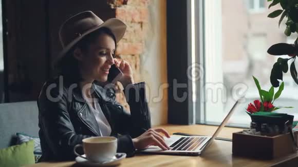 快乐的年轻女子在咖啡馆里用手提电脑打电话视频的预览图