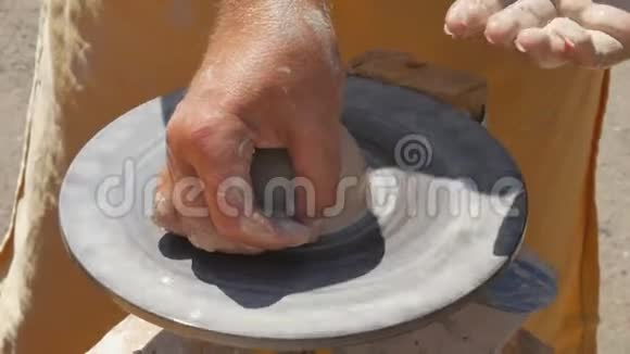 这位雕刻家陶工在街上用粘土做水壶特写扭曲锅的车轮视频的预览图