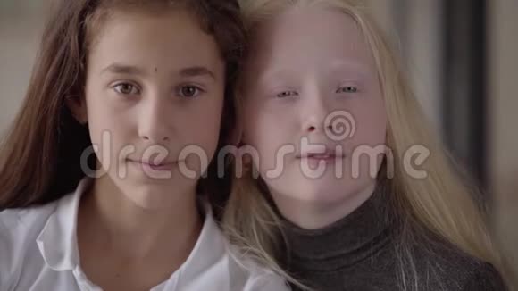 棕色眼睛的黑发女孩和灰色眼睛看镜头的金发女孩的特写肖像概念视频的预览图