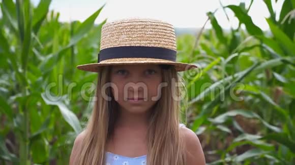 在有机农场的草地上一个戴着草帽的微笑的小女孩正对着镜头快乐小画像视频的预览图
