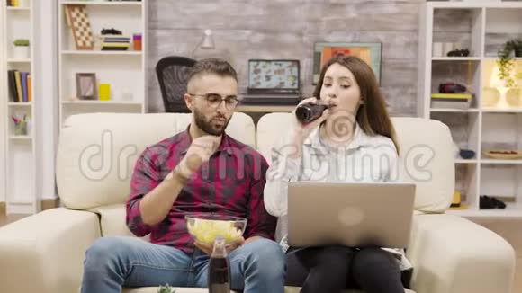 年轻夫妇坐在沙发上喝五高视频的预览图