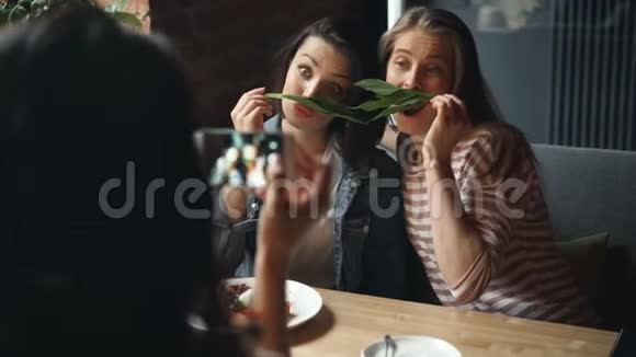 女朋友在咖啡馆里用智能手机摆姿势拍照视频的预览图