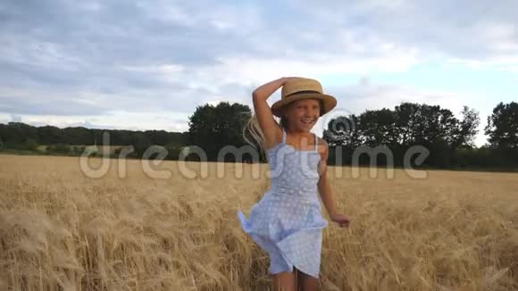 可爱的快乐的孩子戴着草帽在大麦的草地上慢跑一个金发碧眼的漂亮女孩视频的预览图