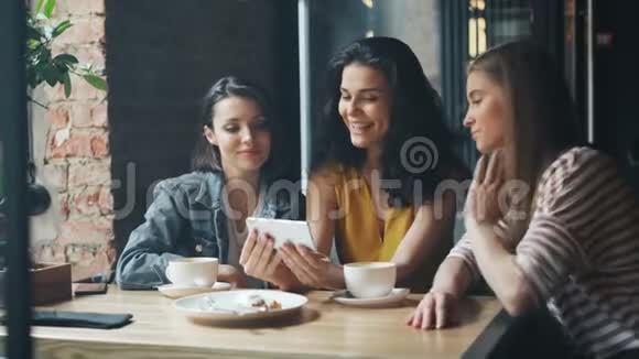 一群年轻女性在咖啡馆里看着智能手机屏幕笑着喝咖啡视频的预览图