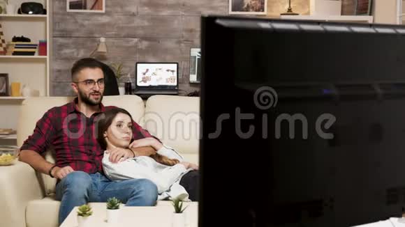 有魅力的年轻夫妇在看电影时在沙发上放松视频的预览图