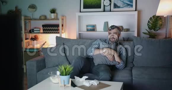 敏感的男人在家看悲伤的电影用纸纸擦拭眼睛视频的预览图