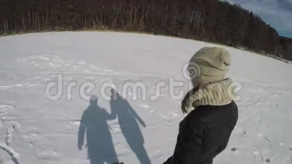 穿着黑色裙子的女孩带着一个男人在雪地里前进视频的预览图