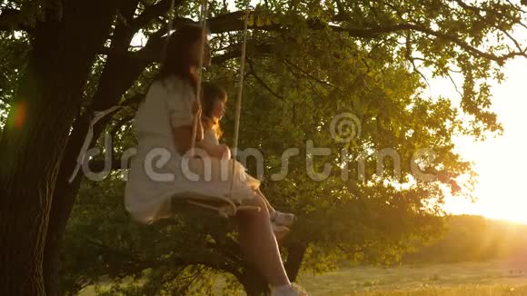 幸福家庭的观念妈妈在阳光下摇动她的女儿妈妈和宝宝骑在秋千上视频的预览图