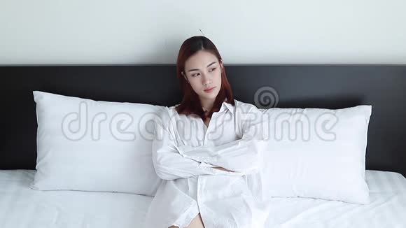可爱的亚洲女人穿着白色睡衣在床上想着什么视频的预览图