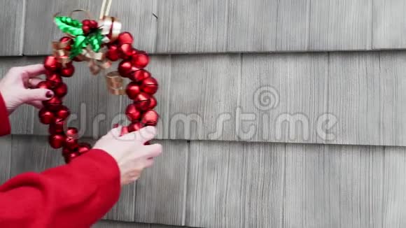 圣诞花环是由一个穿着红色衬衫的女人亲手制作的她把它挂在家里的外面视频的预览图