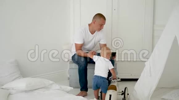父子俩坐在白色的婴儿房里视频的预览图