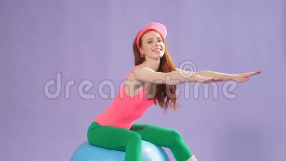 完美身材的女健美操教练双手向前坐在健身球上视频的预览图