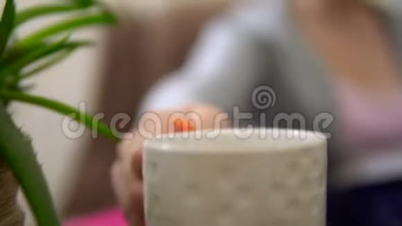 年轻女子喝茶看书扶手椅舒适的客厅舒适的家视频的预览图