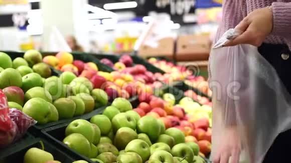 一个漂亮的女孩摘绿色的苹果把它们放进塑料袋里购买适当营养的食物提供视频的预览图