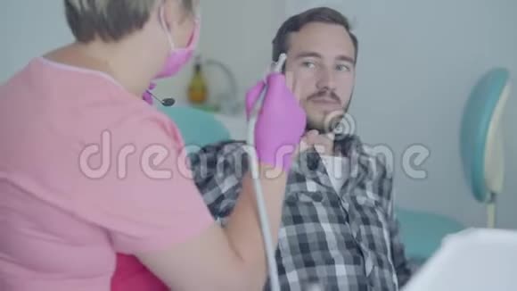 戴着医用口罩和手套的女牙医准备使用医疗工具检查病人的牙齿病人视频的预览图